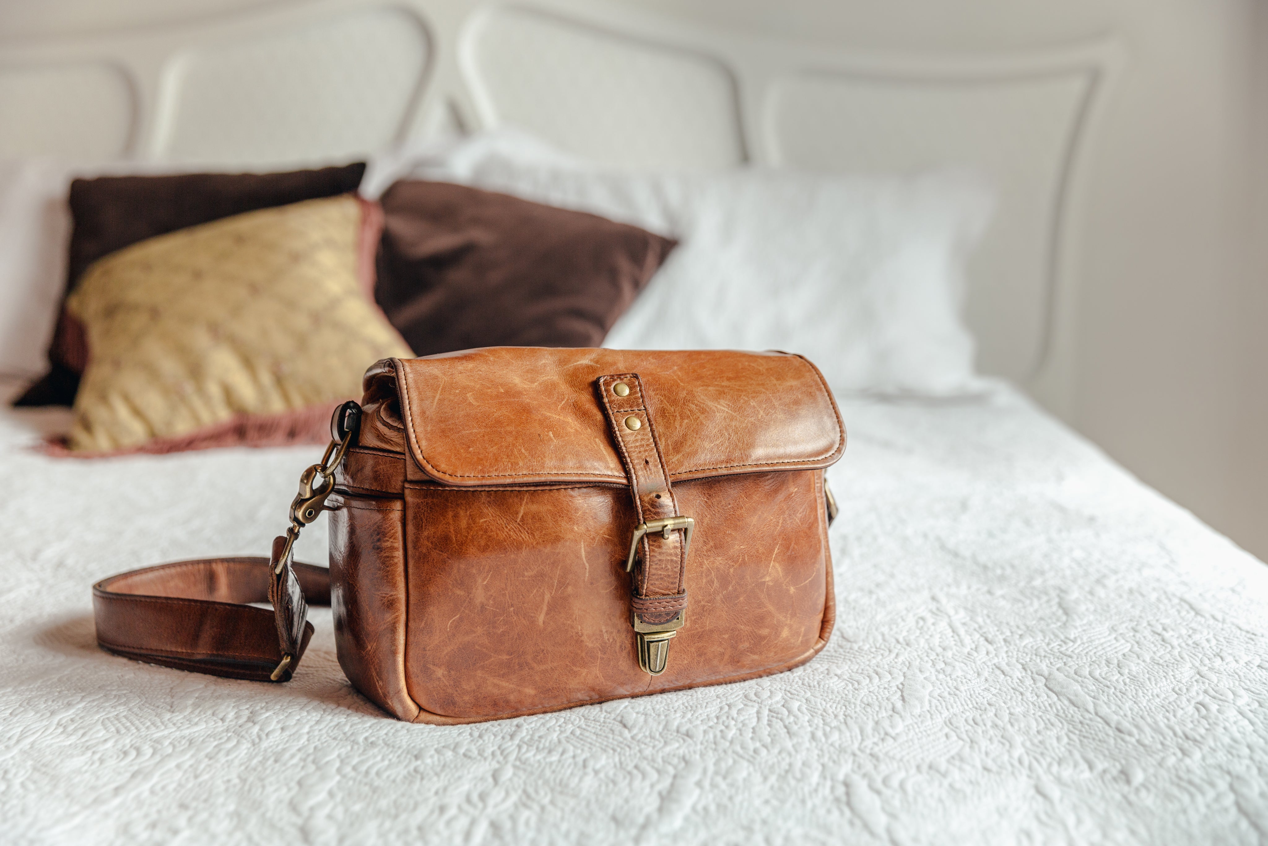 A premium brown leather handbag by Euro Biz shown in a promotional collage with close-up detail panels. The main bag is centered on a dark wooden surface, with inset images showing the interior zip pocket, a hanging leather tag, and the strap detail.